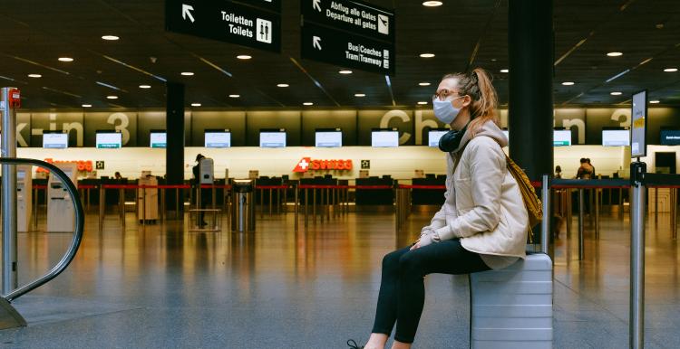 woman sitting in airport with face mask