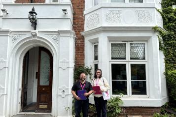 two healthwatch representatives pose outside the practice with their pink clipboards