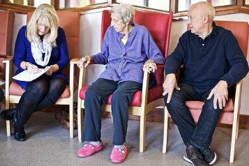 Seated elderly patients and staff with clipboard