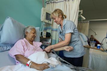 Nurse at patient's bedside on hospital ward