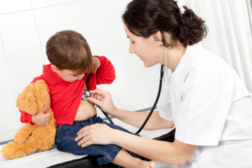 This image depicts a doctor with a stethoscope listening to a kid's heart. The kid is holding his teddy bear.