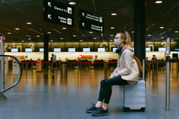 woman sitting in airport with face mask