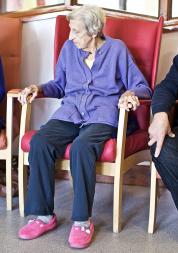 Seated elderly patients and staff with clipboard