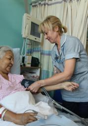 Nurse at patient's bedside on hospital ward
